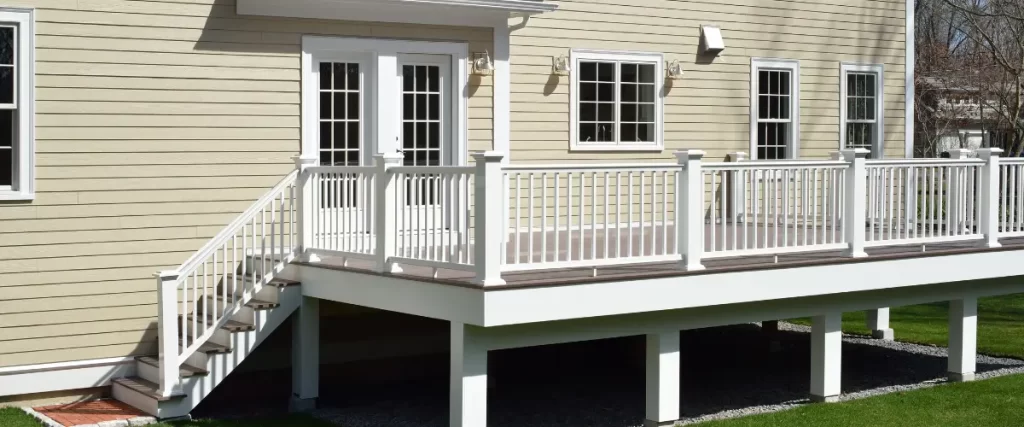 Elevated white deck with stairs and railing on a beige house.