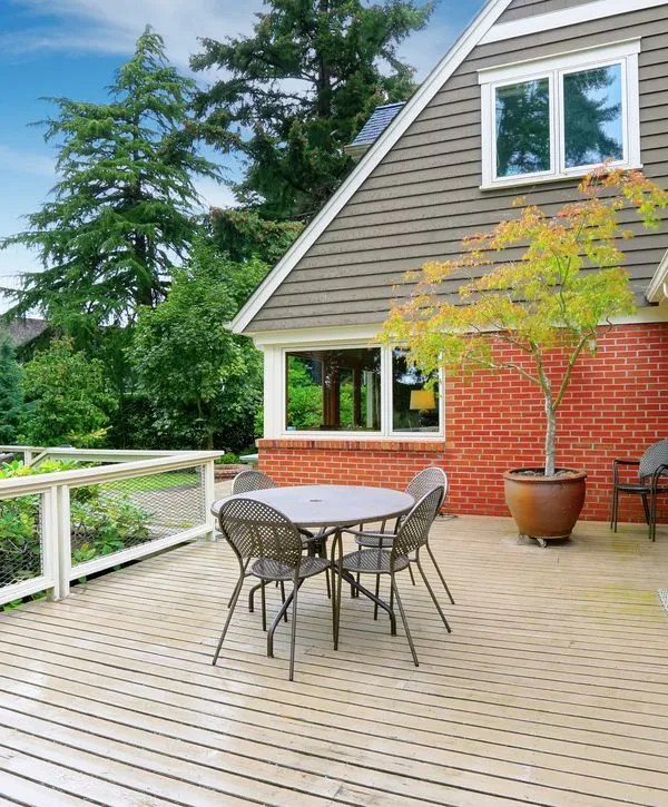 A beautiful, new wood deck featuring a white railing system, designed for outdoor dining and entertaining. This represents professional deck building services offered in Cicero, IN.