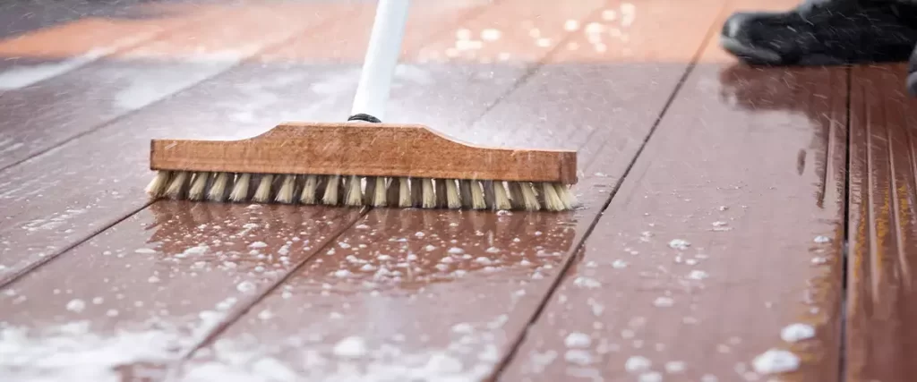 Deck cleaning service removing dirt and buildup with scrub brush and cleaning solution